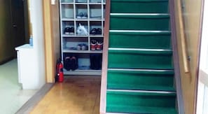 A hallway with a shoe rack and a green carpeted staircase. - Share House Miyabi (Hakodate)