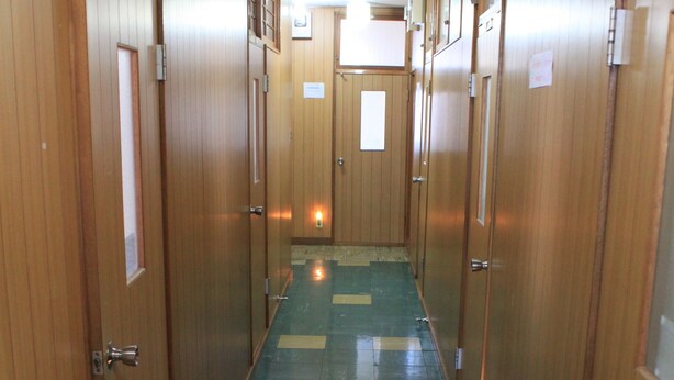 A hotel hallway with wooden doors and a tiled floor. - Share House Miyabi (Hakodate)