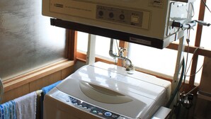 A compact laundry area with a washing machine, a drying machine, and a sink. - Share House Miyabi (Hakodate)
