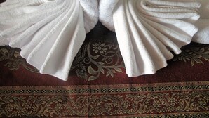 Dos toallas blancas dobladas en forma de cisnes sobre una tela estampada.