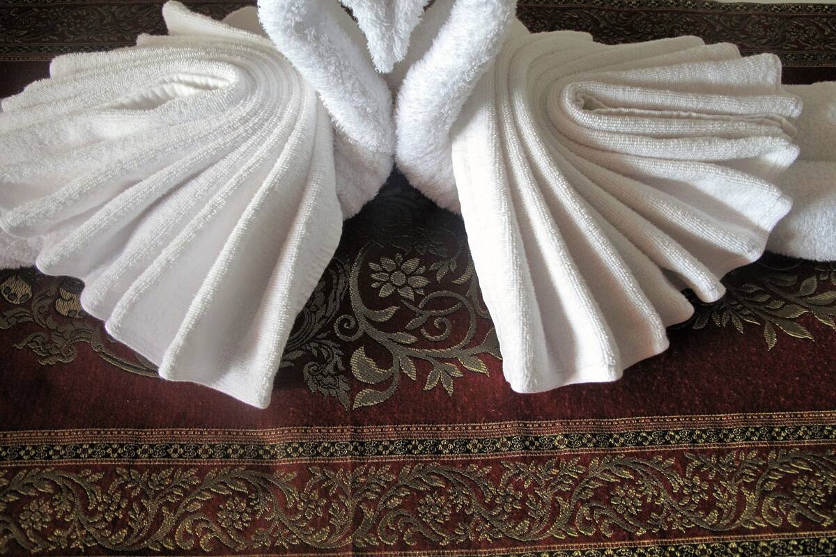 Two white towels folded into swans placed on a patterned fabric.