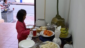 Mesa de buffet con platos de comida, un tostador y una planta verde grande.
