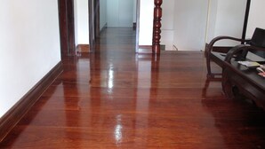 Un pasillo con pisos de madera pulida, una silla de madera y un columnario de madera.
