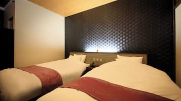 Una habitación de hotel con dos camas, un cabecero con textura y una mesita de noche con lámpara.