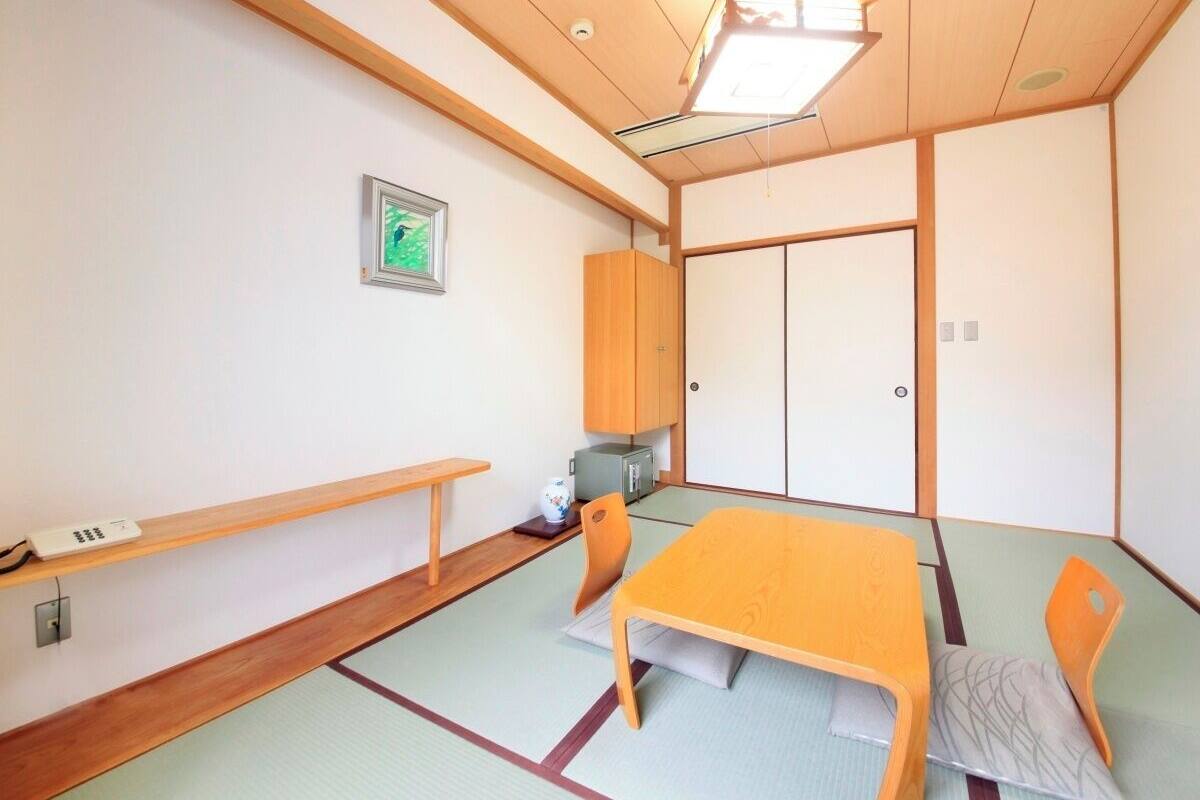 A traditional Japanese room with tatami flooring, a low table with cushions, and sliding doors.