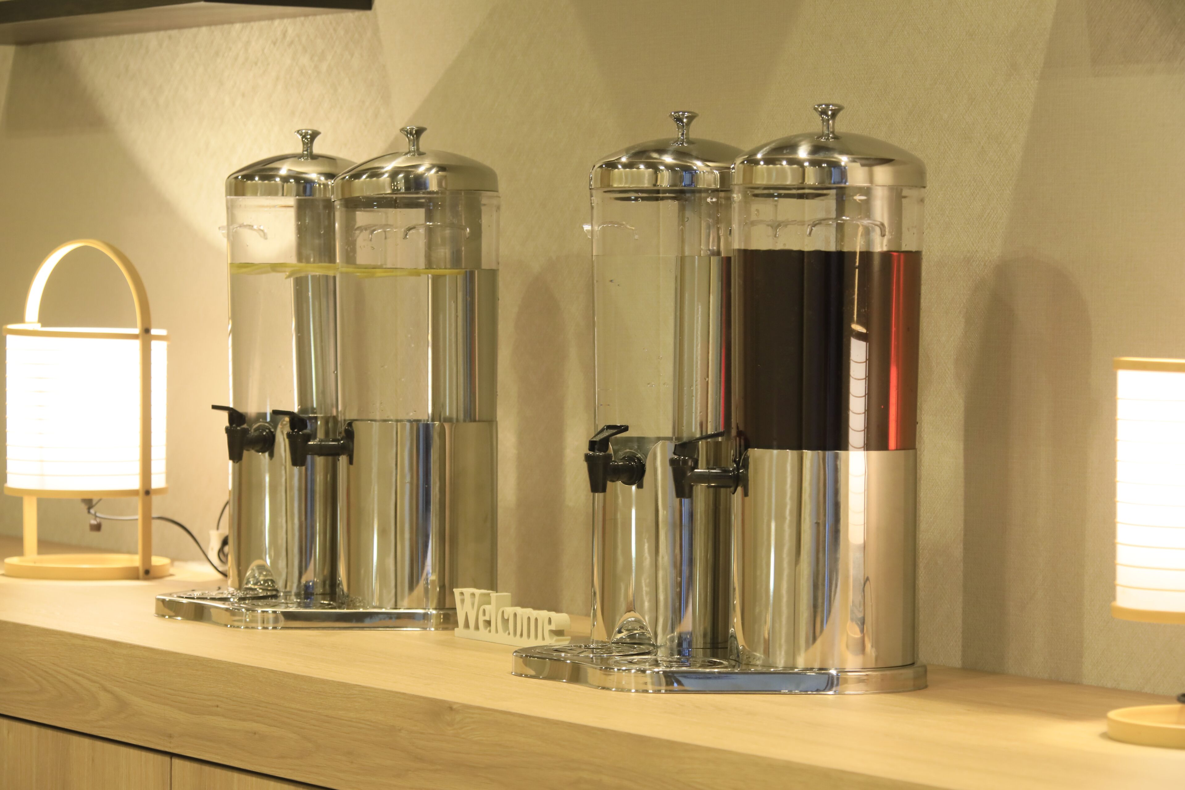 Een rij roestvrijstalen drankdispensers op een houten toonbank.