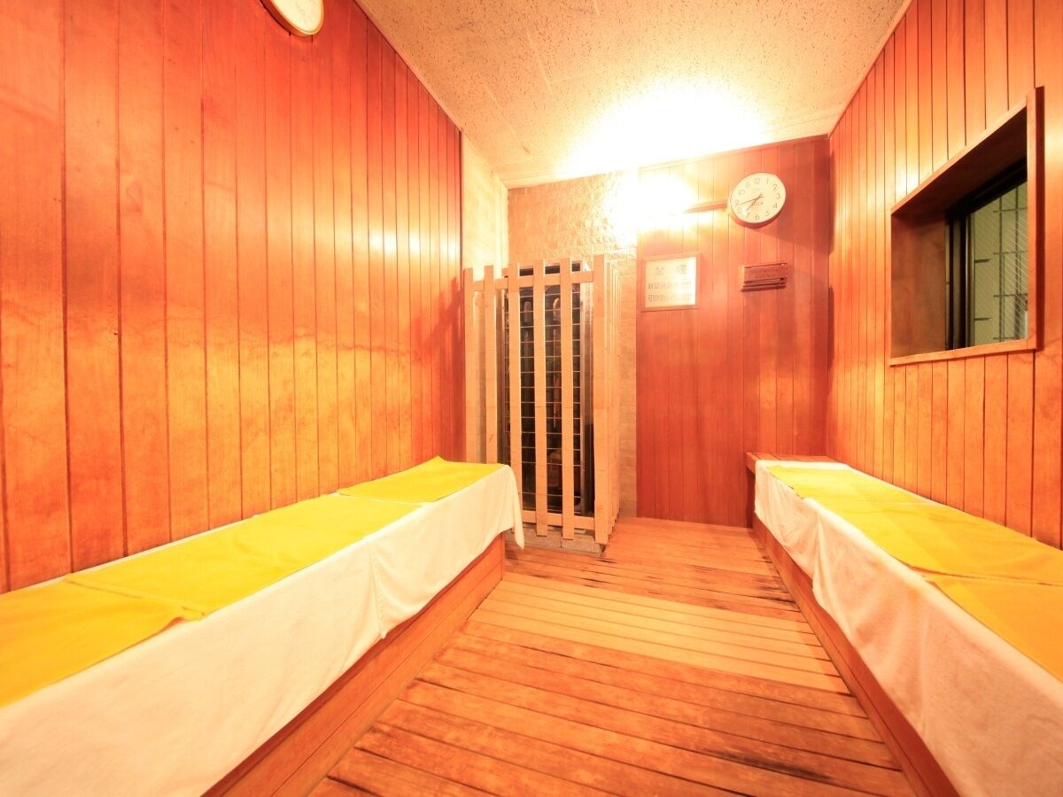 Un sauna con dos bancos de madera, una puerta de madera y un reloj en la pared.