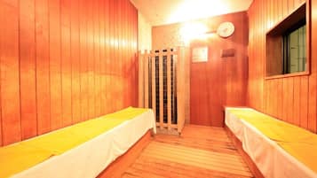 Un sauna con dos bancos de madera, una puerta de madera y un reloj en la pared.