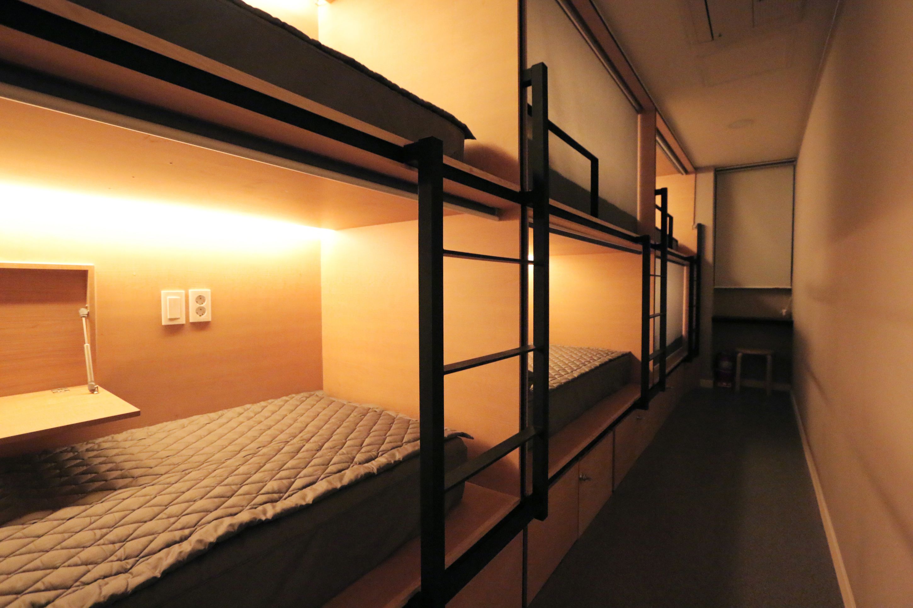A bunk bed room with a desk and a lamp.