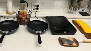 A kitchen counter with two frying pans, a basket of eggs, a bottle of oil, and a portable stove. - Blueboat Hostel Gyeongju (Gyeongju)