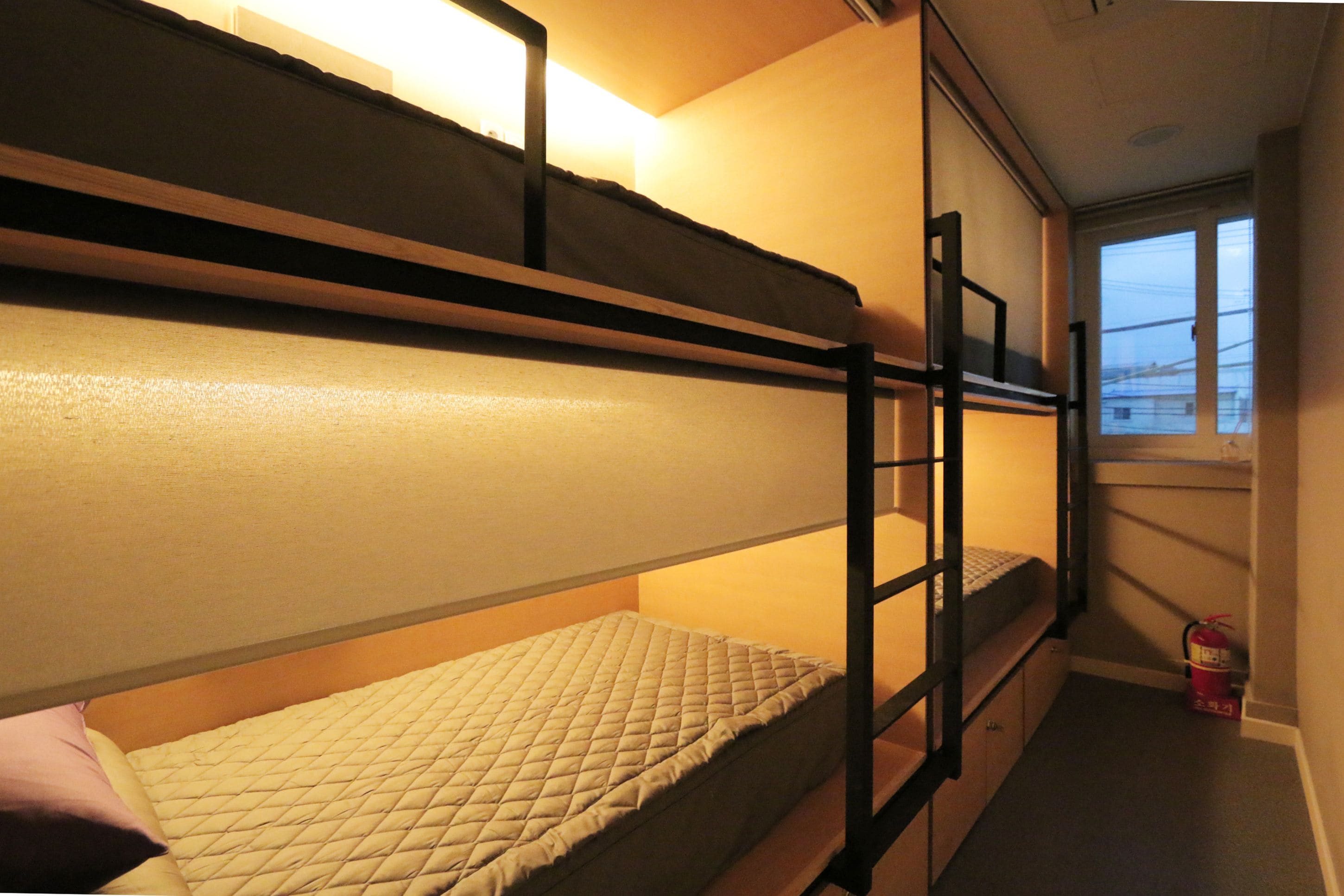 A bunk bed room with a window and a fire extinguisher.
