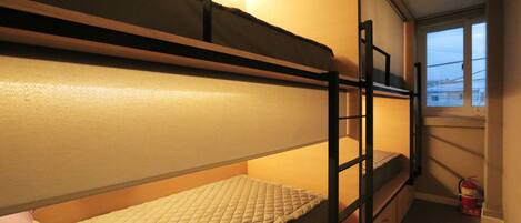 A bunk bed room with a window and a fire extinguisher.