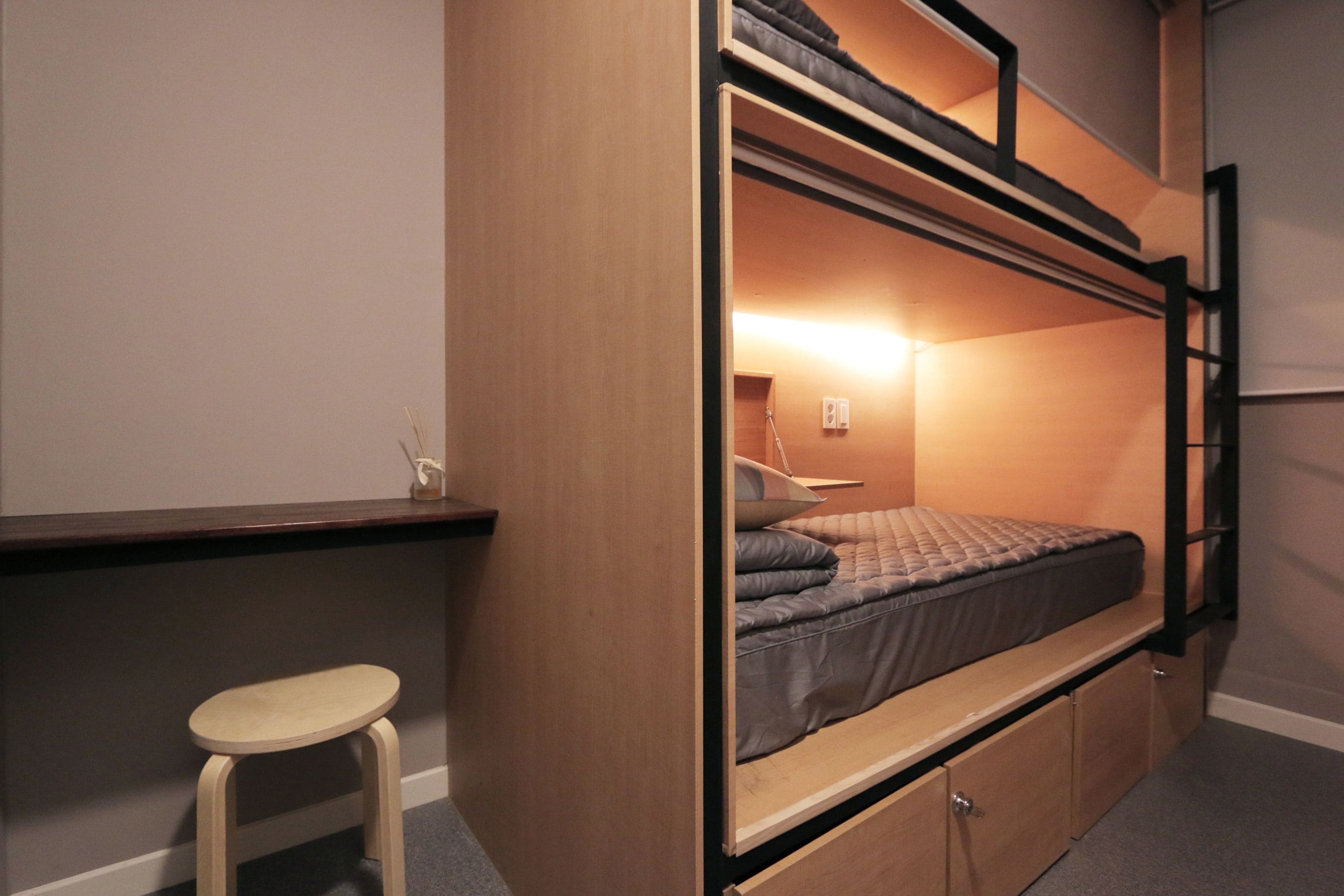 Habitación con literas, escritorio y taburete.