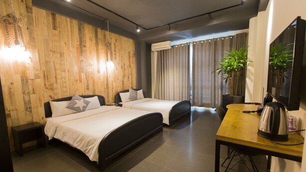 A hotel room with two beds, a wooden wall, a desk with a kettle, and a TV. - A in Hotel (Ho Chi Minh City)