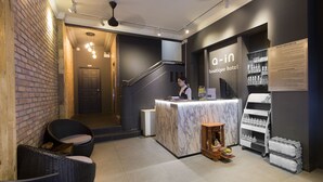 A boutique hotel lobby with a reception desk, wicker seating, a staircase, and a display of glasses. - A in Hotel (Ho Chi Minh City)