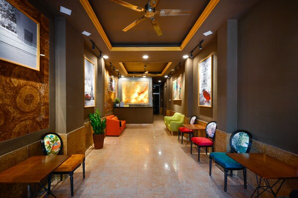 Un vestíbulo de hotel con una recepción central, zona de estar con sillas y mesas, y obras de arte en las paredes.