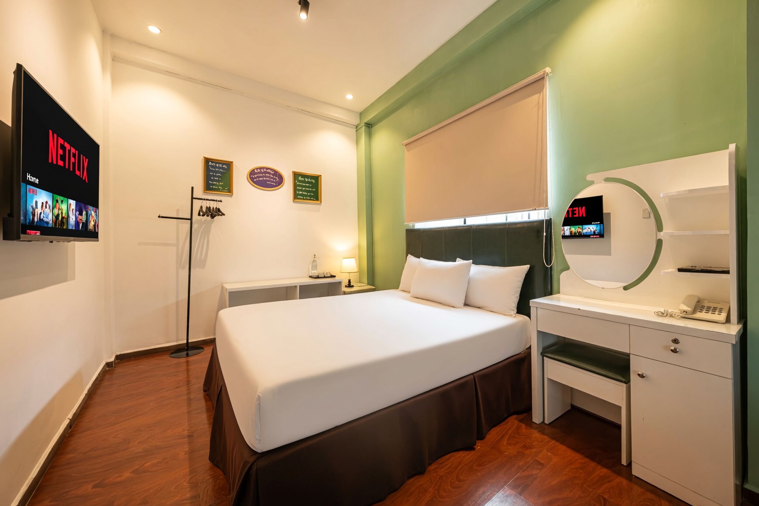 Habitación de hotel con cama, escritorio, televisor y espejo.