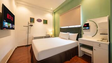 Habitación de hotel con cama, escritorio, televisor y espejo.