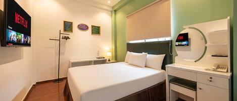A hotel room with a bed, a desk, a TV, and a mirror.