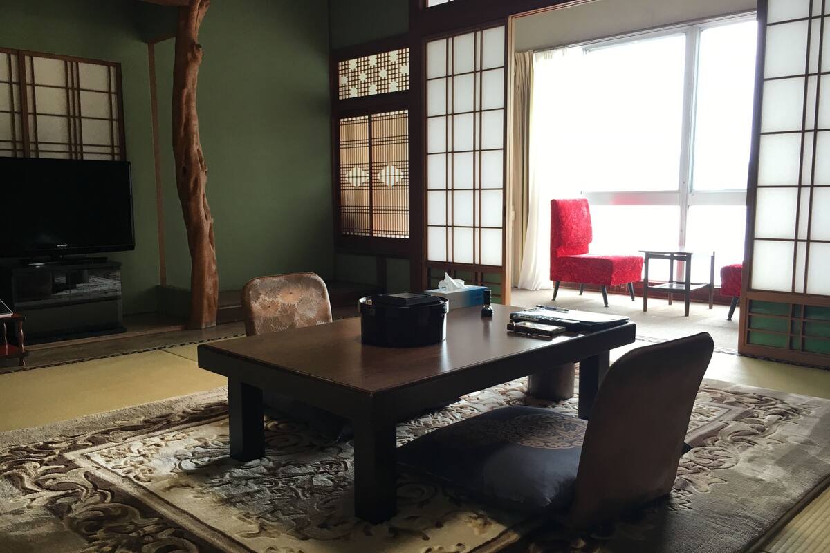 A traditional Japanese-style room with tatami flooring, a low table, and shoji screens.