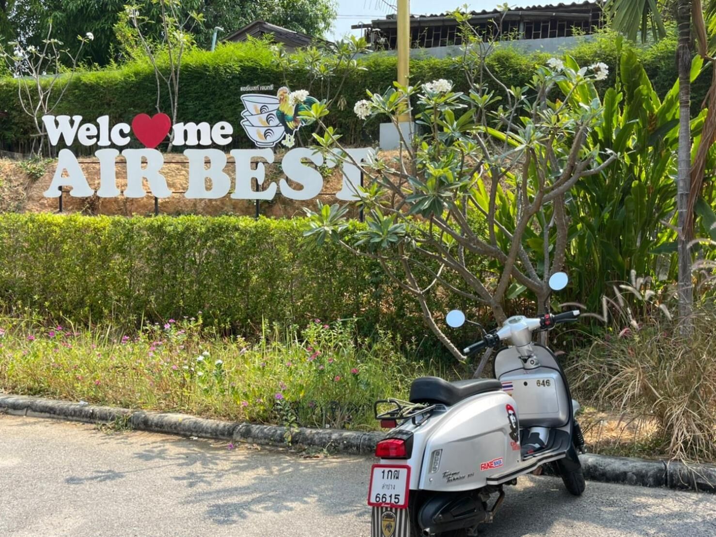 A scooter parked in front of a sign that reads 'Welcome AIR BEST' with a heart symbol.