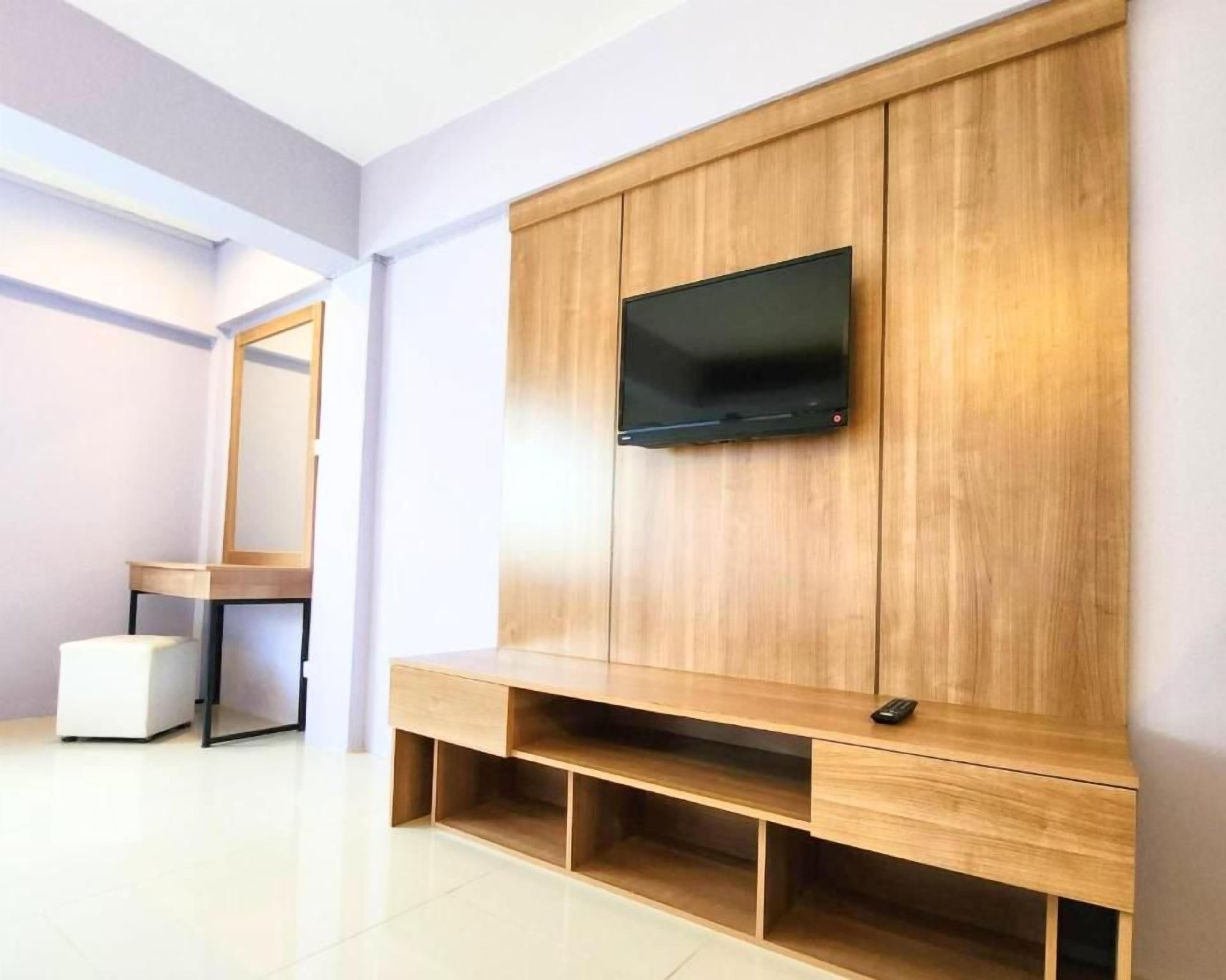 A modern room with a wooden entertainment unit, a flat-screen TV mounted above it, and a small white table with a chair.