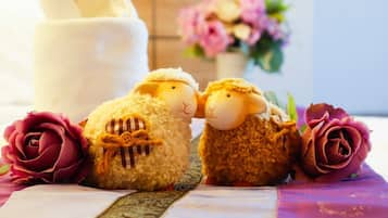 Two plush sheep toys on a table with a white cloth and a decorative ribbon.