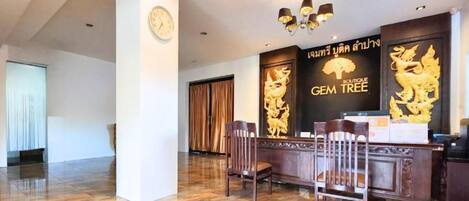 A reception area with a reception desk, chairs, a clock, and a wall with a logo and text.