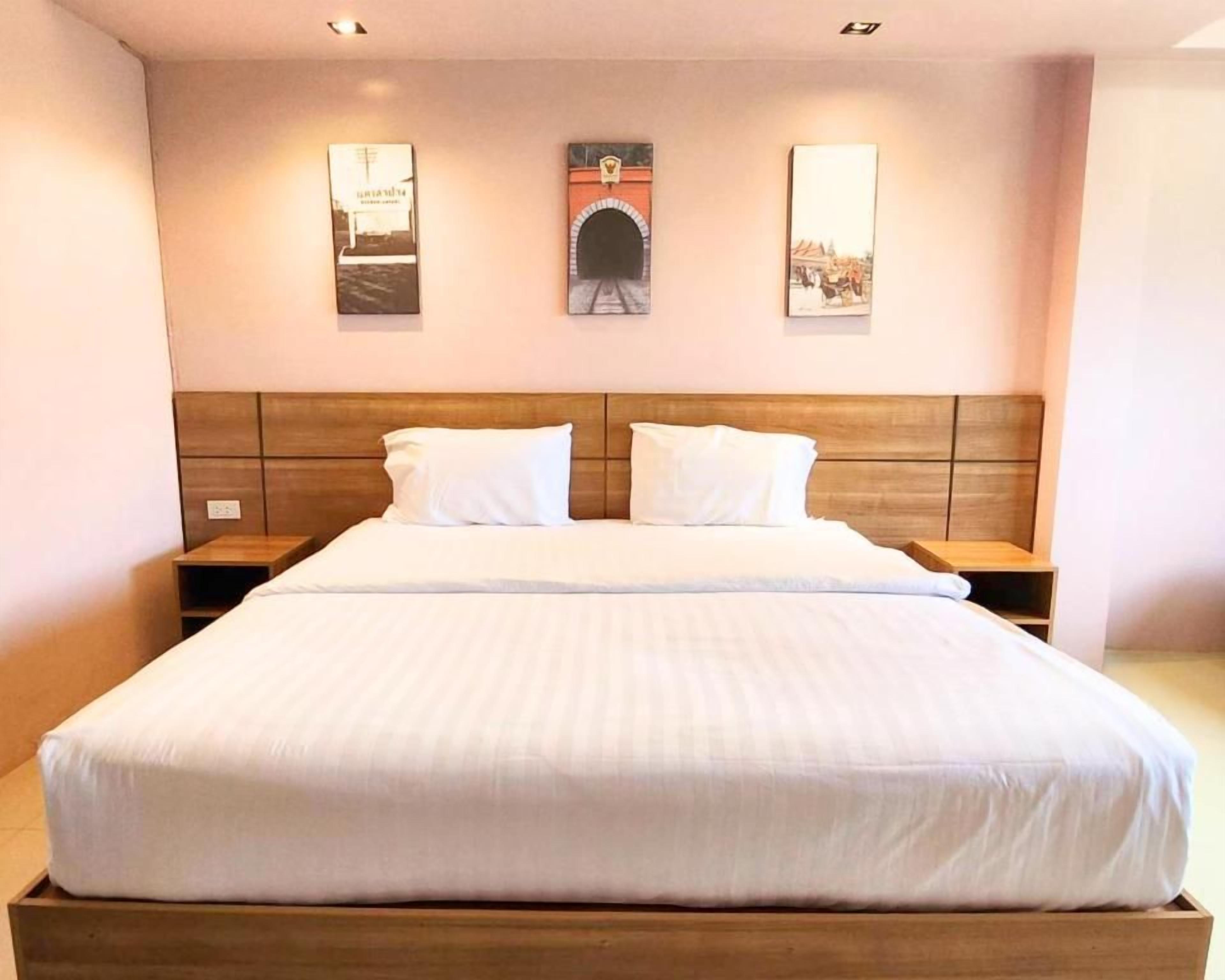 A hotel room with a large bed, wooden headboard, two bedside tables, and three framed pictures on the wall.