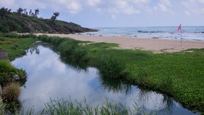 A beach with a calm stream, a red flag, and a clear sky. - LoveSea 126 House Inn (Hengchun)