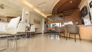 A modern cafe with white leather chairs, a wooden counter, and a large mirror. - LoveSea 126 House Inn (Hengchun)