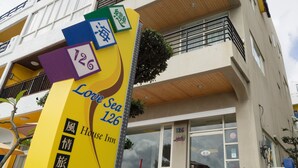A hotel with a yellow sign indicating room number 126, a name in English and another language, and a contact number. - LoveSea 126 House Inn (Hengchun)