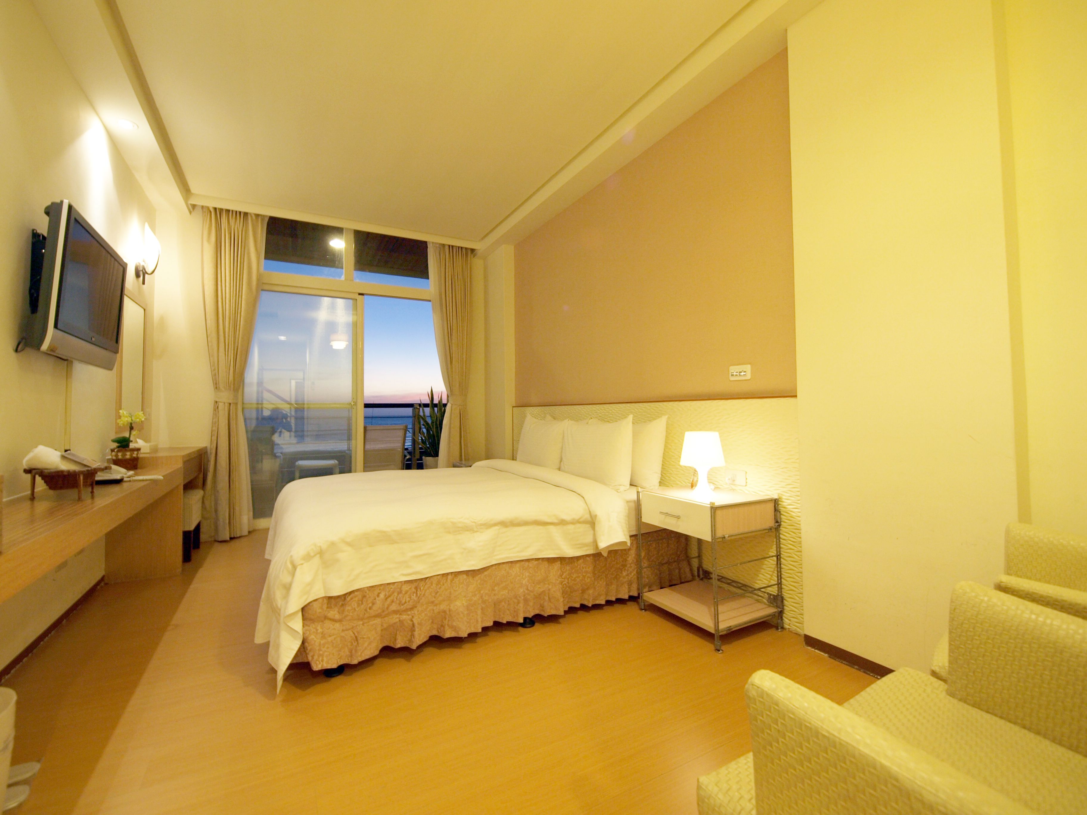 Habitación de hotel con cama, mesita de noche, silla y televisión en la pared.