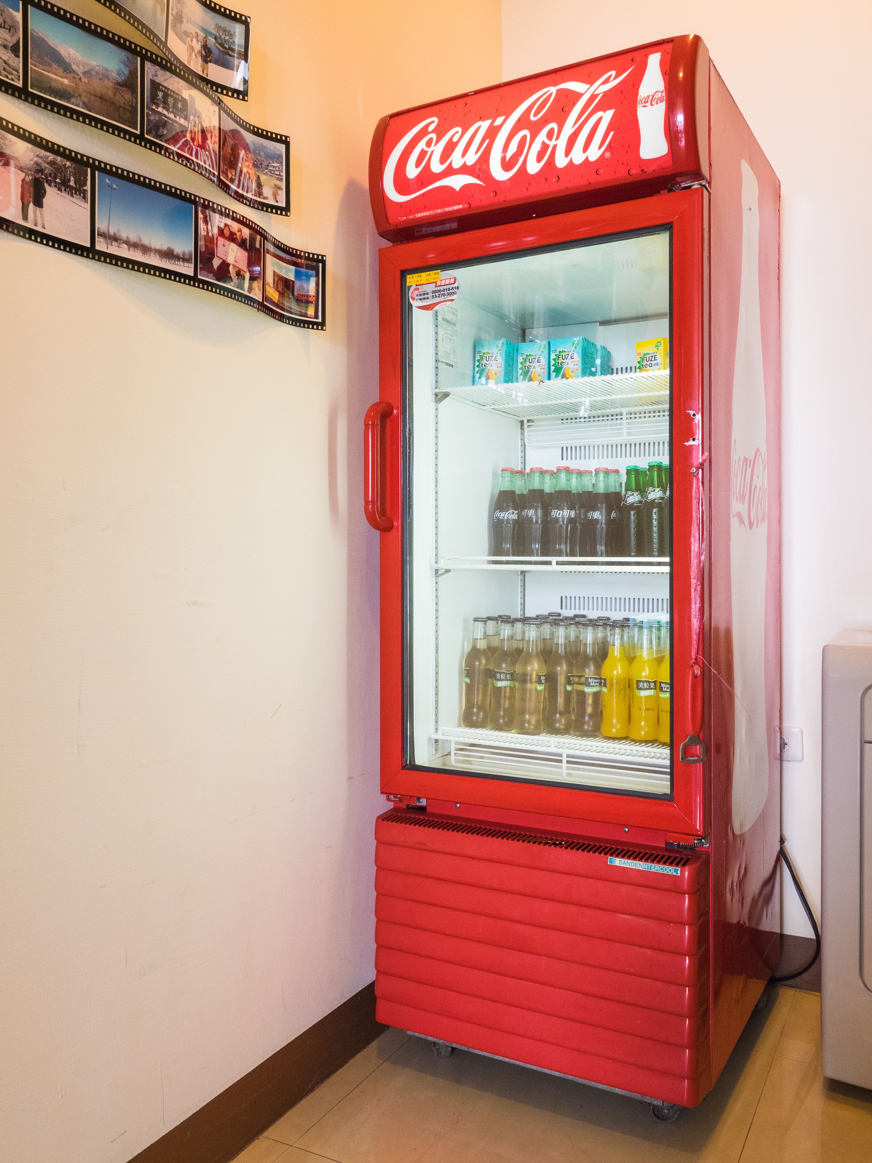 A red Coca-Cola vending machine with a glass door, containing various beverages.