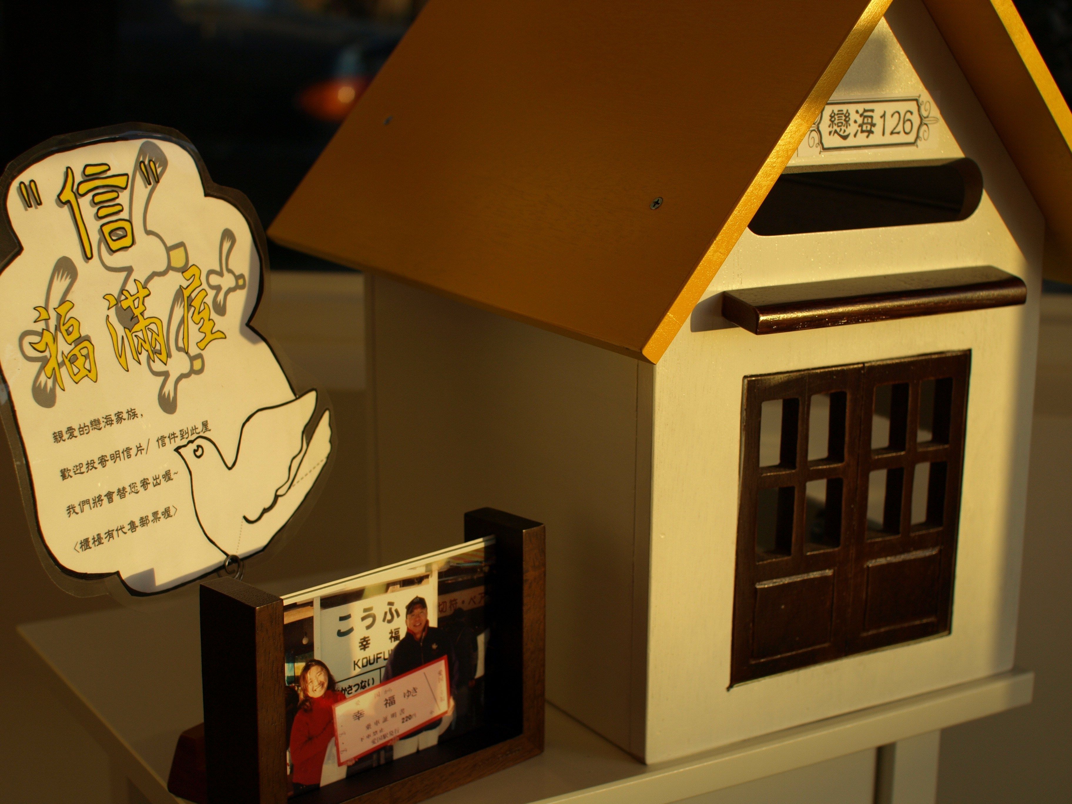 A model house with a sign reading "海 126" and a display of a man and woman holding a check.