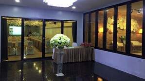 Un vestíbulo de hotel con una recepción, un arreglo floral grande y una zona de estar con sillas y mesas.