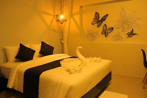 A hotel room with a bed, pillows, a wall-mounted light fixture, and butterfly wall art. - IPOWER Chiang Rai (Chiang Rai)