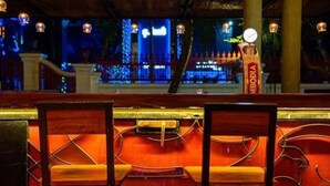 A bar area with wooden chairs and a counter. - Base Villa Phnom Penh - Hostel (Phnom Penh)
