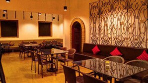 A restaurant with a bar area, multiple tables, and a decorative wall. - Base Villa Phnom Penh - Hostel (Phnom Penh)