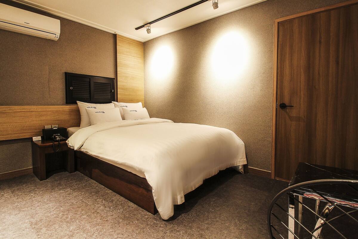 Une chambre bien rangée, avec un lit, des tables de chevet, une armoire et un appareil de climatisation.
