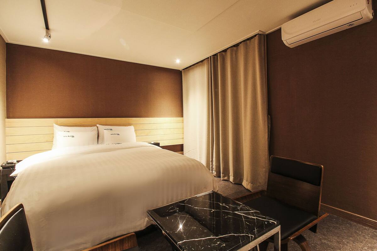 Une chambre d’hôtel avec un lit, une table de chevet et une chaise.