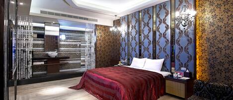Un dormitorio moderno con una cama grande, una mesita de noche, un sofá y un espejo decorativo.