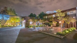 Un patio bien iluminado con zona de estar, plantas en macetas y un edificio de fachada moderna.