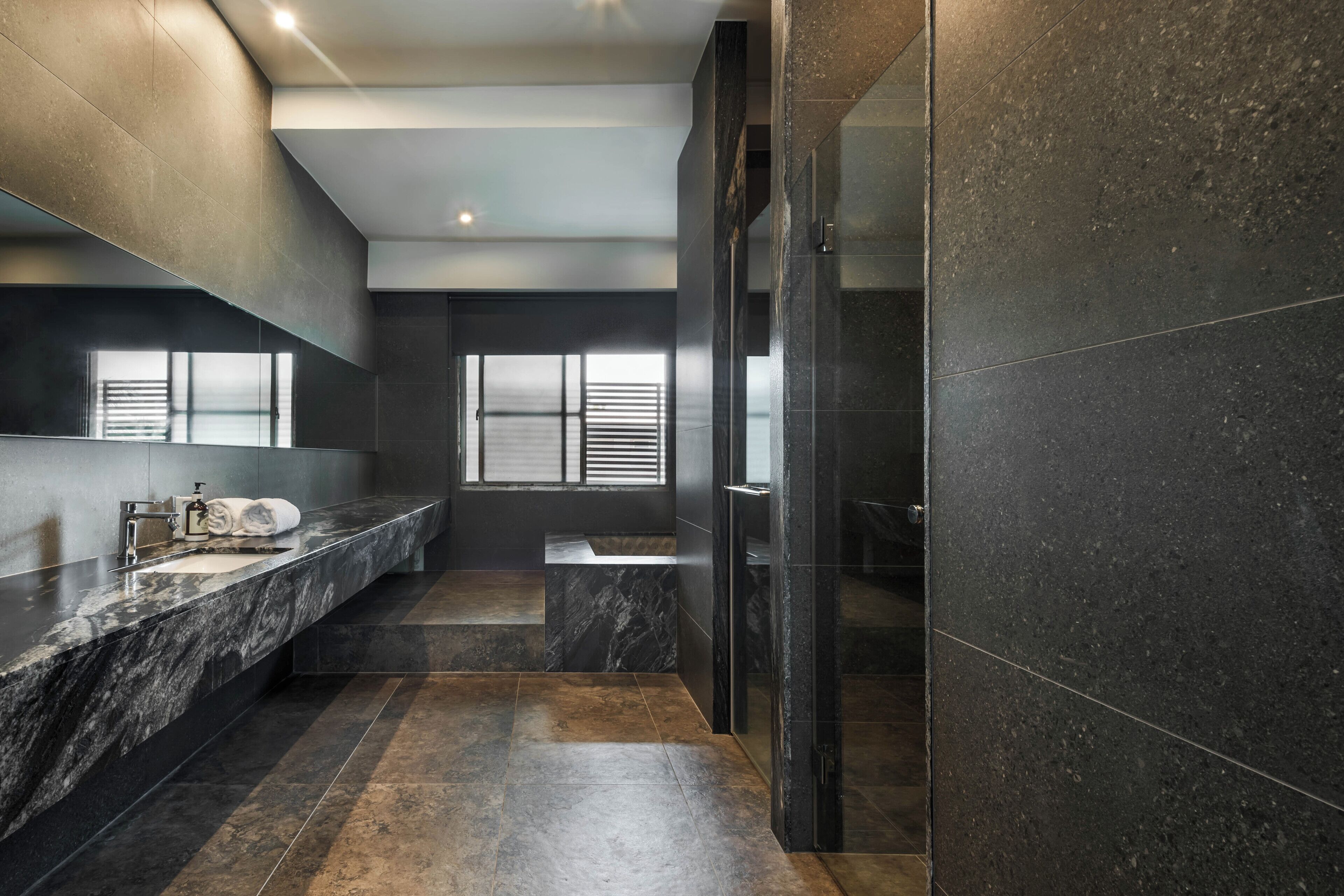Un baño moderno con encimera de mármol, cabina de ducha de cristal y un espejo grande.