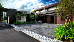 Una casa moderna con un patio empedrado, mobiliario exterior y un jardín.