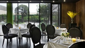 Un restaurante con mesas dispuestas para comer, sillas y un jarrón con flores.