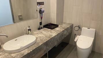 Een moderne badkamer met een marmeren wastafel, een spiegel, een haardroger en een toilet.