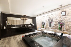 A modern bathroom with a black vanity, a large mirror, a stone wall, and a checkered floor. - Feng Cai Motel (Yuanlin)