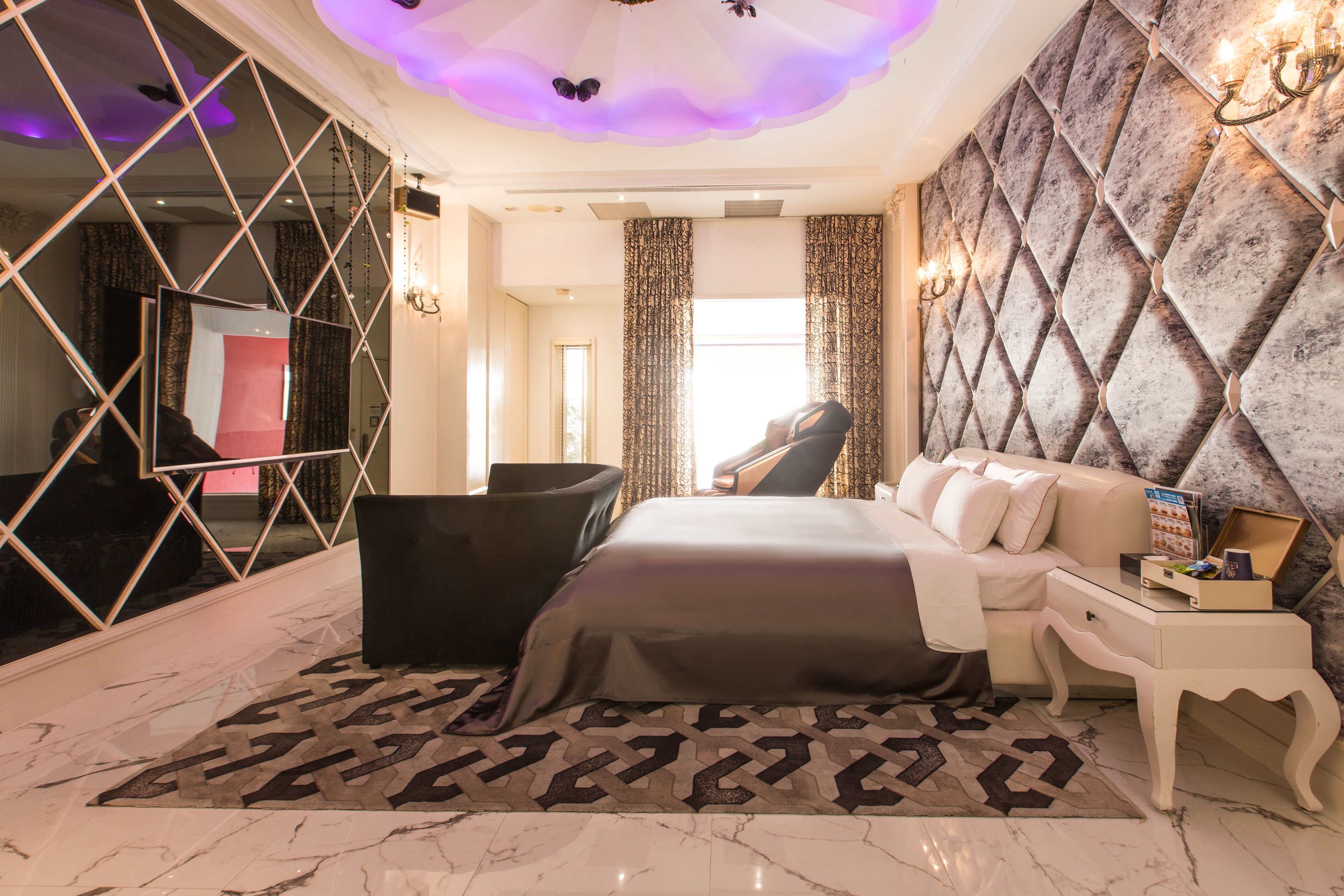 Une chambre à coucher luxueuse avec un grand lit, un coin salon et un miroir.