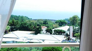 A view from a window overlooking a residential area with houses, trees, and a bridge. - Hera's Castle (Seogwipo)